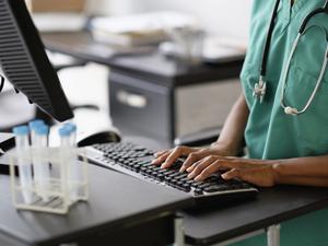 Mixed race nurse working at computer