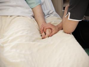 Nurse holding hands with elderly patient.