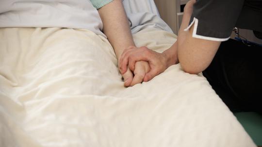 Nurse holding hands with elderly patient.