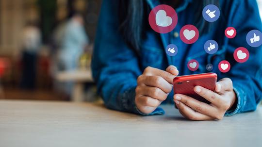 Midsection Of Woman Using Smart Phone On Table In Cafe