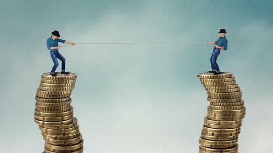 Two men on top of coins in tug of war, business competition concept