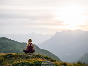 Woman performs yoga moves on mountain summit