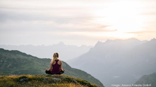 Woman performs yoga moves on mountain summit