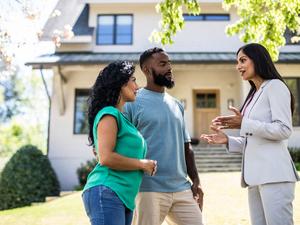 Couple meeting with real estate agent in front of home