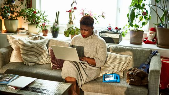 Woman working from home on sofa with laptop