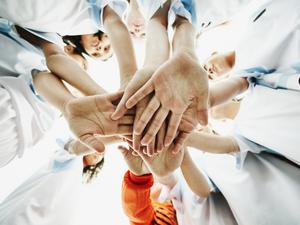 View from below of young female soccer players bringing hands together before game