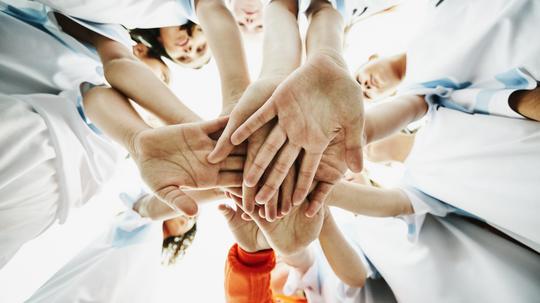 View from below of young female soccer players bringing hands together before game