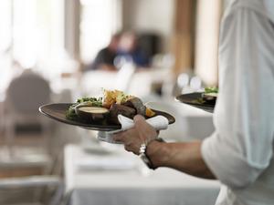 Close-up of waiter walkiing with dishes