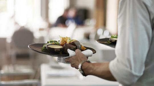 Close-up of waiter walking with dishes