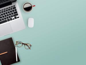 High Angle View Of Laptop With Book And Eyeglasses On Blue Table