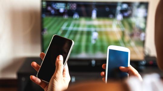 Friends using mobile phone during a tennis match