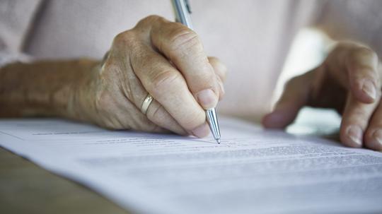 Senior woman's hand signing a document, close-up