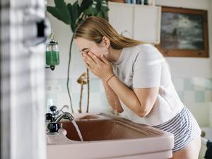 Woman in bathroom washing face