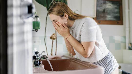 Woman in bathroom washing face