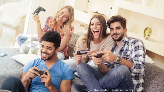 Smiling friends playing video games at home