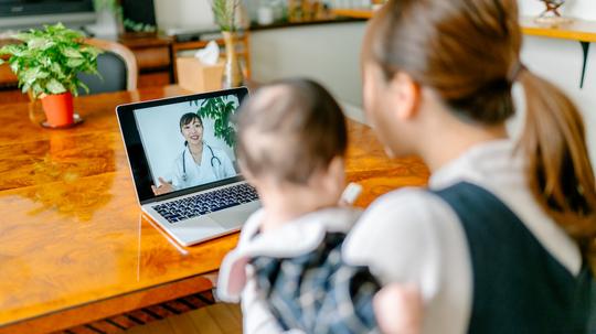 Mother with her baby video calling doctor from home