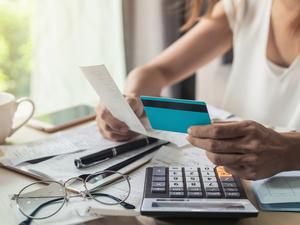 Midsection Of Businesswoman Holding Credit Card And Bill While Working At Desk