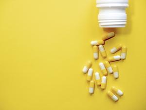 Many yellow and white pills on yellow background