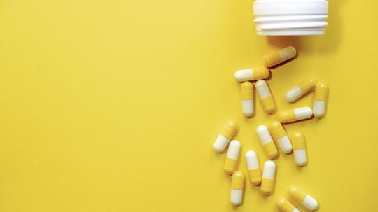 Many yellow and white pills on yellow background