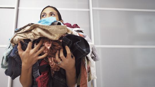 Young woman holding pile of laundry, low angle view