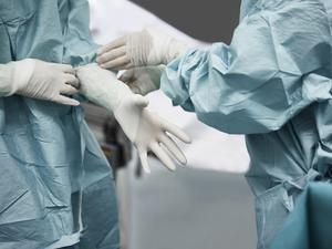 Female doctor helping surgeon wearing glove