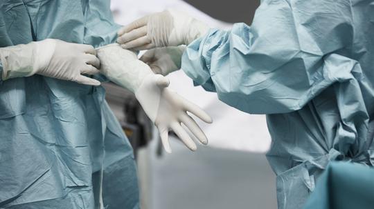 Female doctor helping surgeon wearing glove