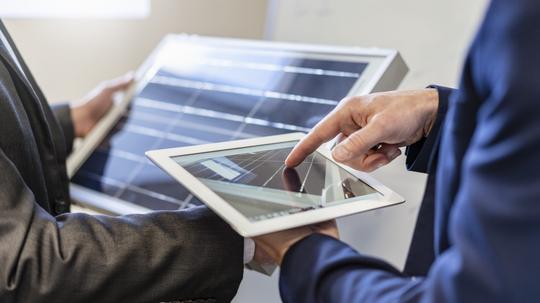 Close-up of two businessmen in office with solar cell and tablet