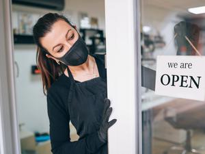 Happy business owner hanging an open sign during COVID-19