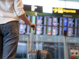 Female traveller standing in front of Flight display schedule in the International airport