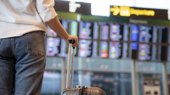 Female traveller standing in front of Flight display schedule in the International airport