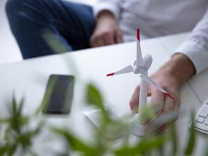 Close-up of man with hand on wind turbine model on table