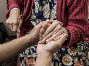 Nurse holding hands with elderly patient.