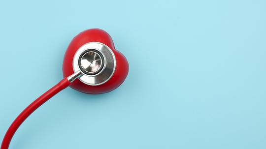 High Angle View Of Red Heart Model With Stethoscope Over Blue Background