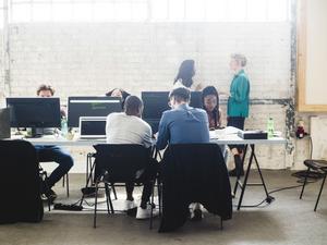 Young computer programmers coding at desk in creative office