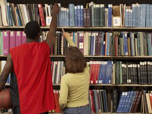 Students reaching for books in library