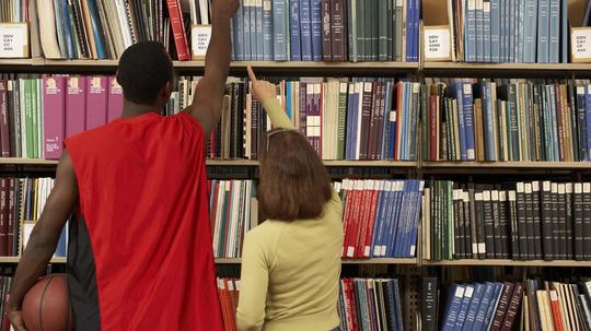 Students reaching for books in library