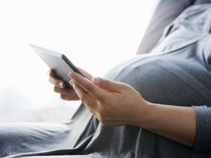 a pregnant woman using a digital tablet