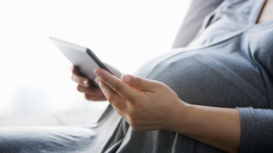 a pregnant woman using a digital tablet