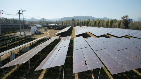 View of solar farm in sunlight with blue sky, dirty solar cell  array, green energy concept.