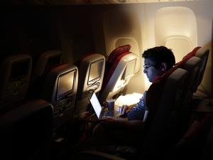 man looking at laptop, on an aircraft.