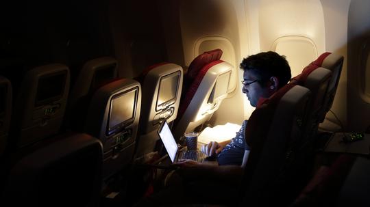 man looking at laptop, on an aircraft.