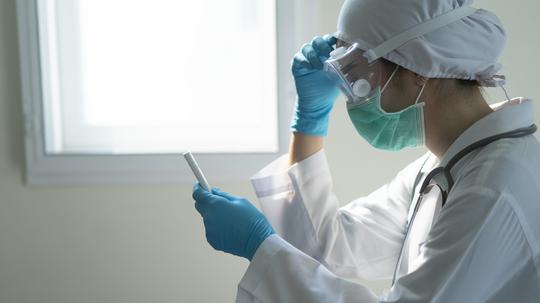 Closeup Asian female Doctor wearing face shield and PPE suit and stressed for stop Coronavirus outbreak or Covid-19, Concept of Covid-19 quarantine