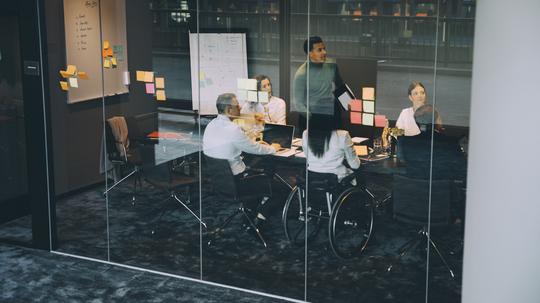 Confident businessman explaining strategy to colleagues in board room at office