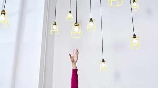 A hand reaching for conceptual idea lightbulbs