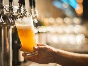 Cropped hand of bartender filling beer from tap at bar