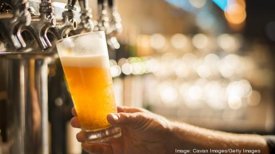 Cropped hand of bartender filling beer from tap at bar