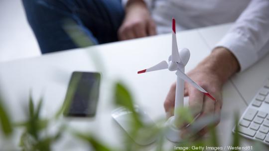 Close-up of man with hand on wind turbine model on table