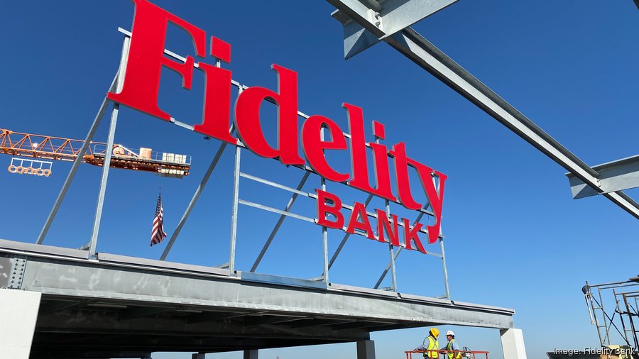 Crews perch red Fidelity Bank sign on top of nearly finished downtown