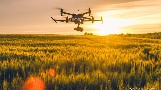 Drone flying over field at sunset