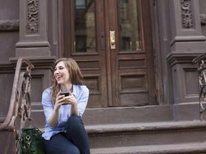 Young woman in steps of building with cellphone